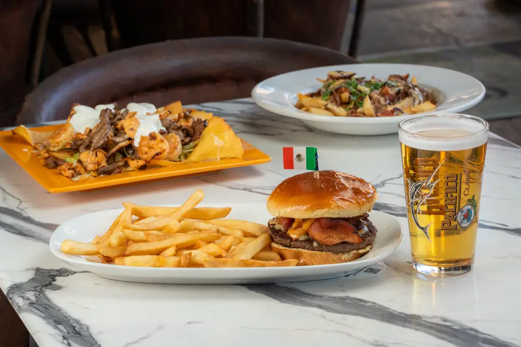 Bacon burger with a Mexican flag pick, fries and a beer