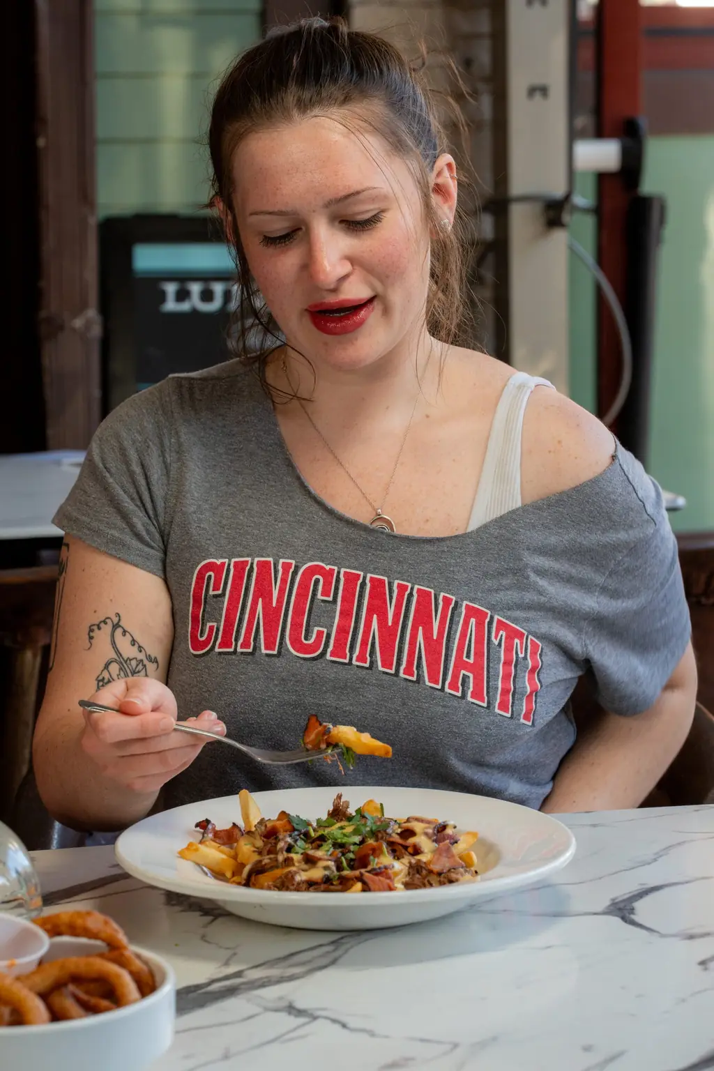 A guest in a Cincinnati shirt eating loaded fries