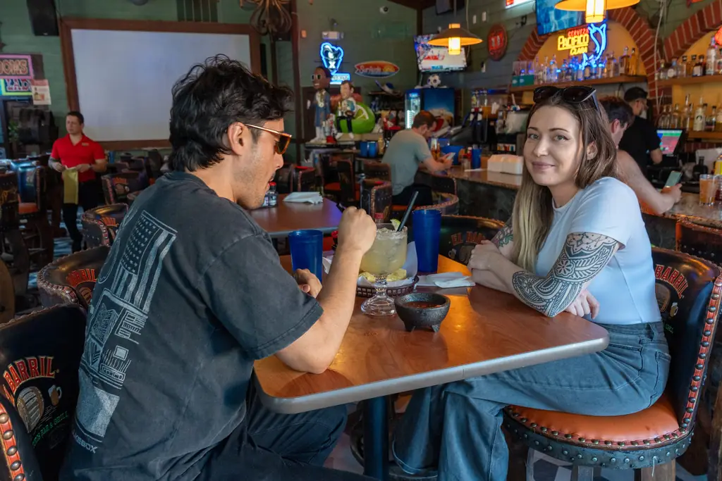 Guests at a table in the Mt Adams bar room with TVs behind