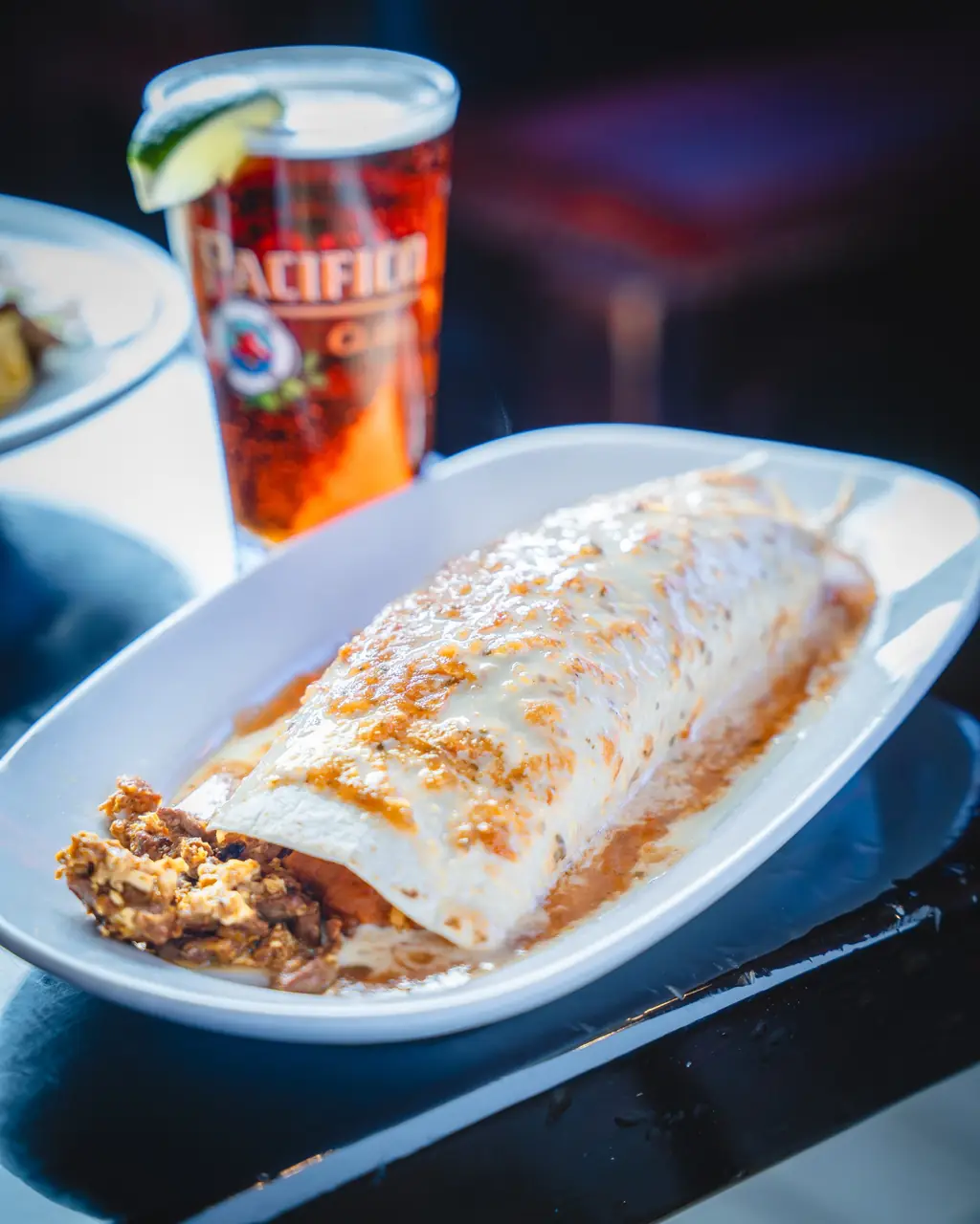 Burrito Borracho smothered in sauce with a beer behind