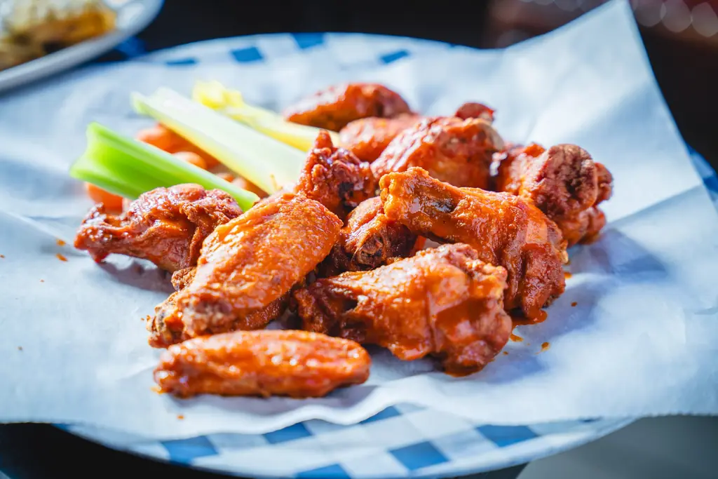 Buffalo wings with celery on checkered paper
